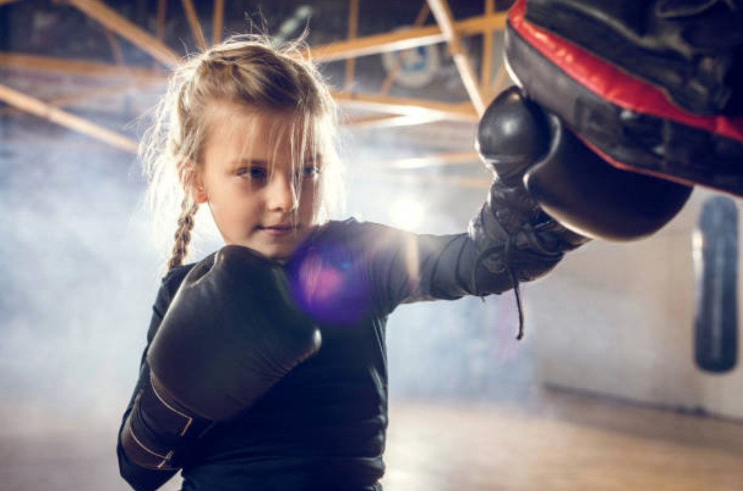Tween girl boxing wearing black long sleeved shirt and boxing gloves
